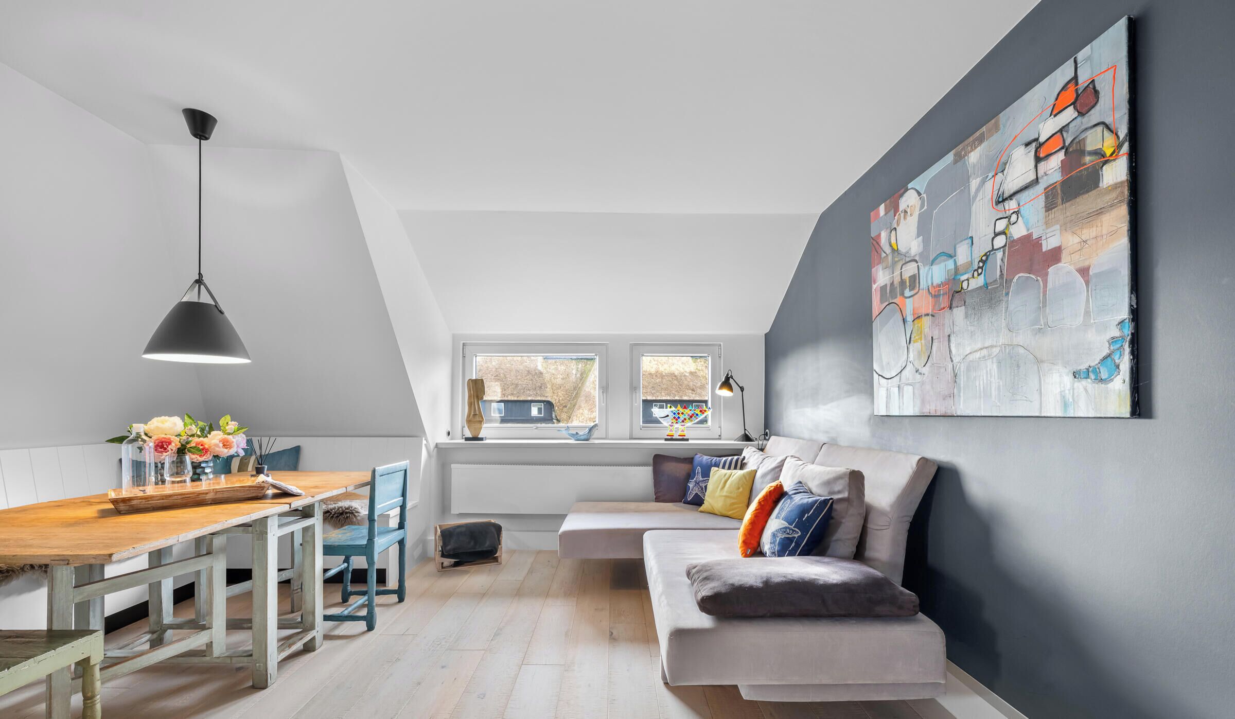 Ein modernes Loft mit Essbereich, einer Couch und einem großen abstrakten Gemälde.