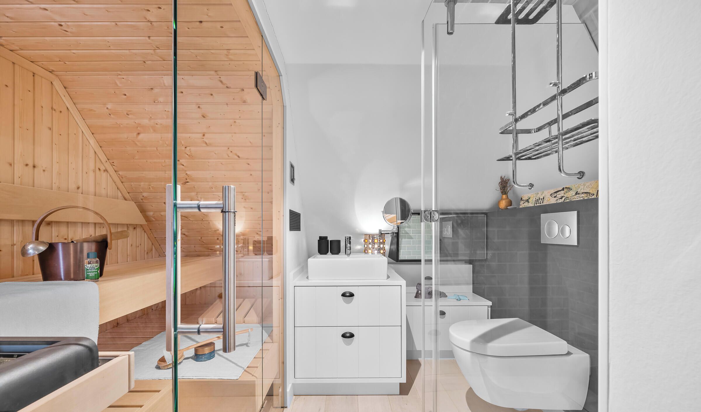Un baño moderno con cabina de ducha de vidrio, un lavabo blanco y un inodoro.