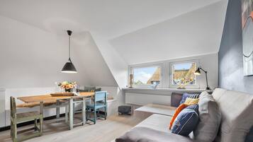 Ein Loft-Zimmer mit Essbereich, einer Couch und einem Fenster mit Blick auf Gebäude.
