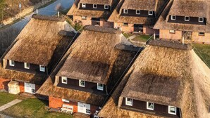 A cluster of thatched-roof cottages with a narrow road leading up to them. - High-quality vacation apartment in List on Sylt by the beach, with sauna and parking space (List auf Sylt)