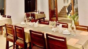 Comedor con varias mesas dispuestas para comensales, con sillas de madera y una paleta de colores neutros.