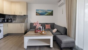 A modern living space with a kitchen, grey sofa, and a painting of a coastal landscape. - Holiday Home 'Salou Blueme' with Mountain View, Wi-Fi and Air Conditioning (Salou)
