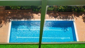 A swimming pool with a tiled border, surrounded by a grassy area and a brick wall. - Holiday Home 'Salou Blueme' with Mountain View, Wi-Fi and Air Conditioning (Salou)