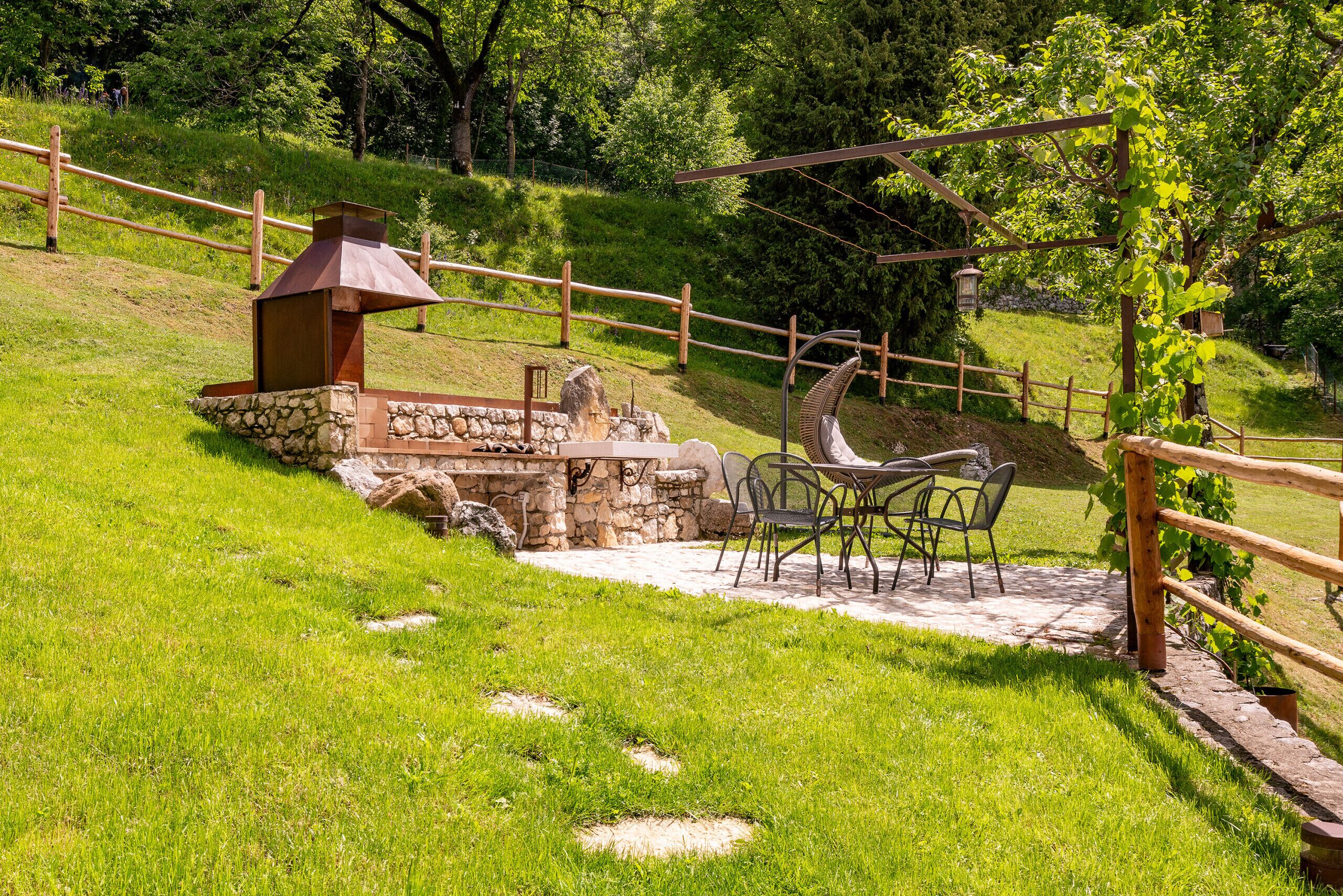 Un patio con chimenea de piedra, mobiliario exterior y valla de madera.