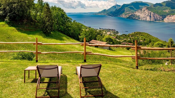 Un espace extérieur aménagé avec des chaises et une table, offrant une vue pittoresque sur un lac et des montagnes.