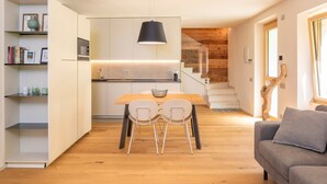 Une cuisine moderne avec une table et des chaises, un escalier menant à un autre niveau, et un canapé dans l’espace salon.