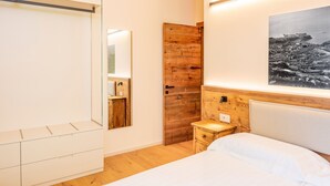 Une chambre à coucher comprenant un lit, une armoire en bois, une petite table de chevet, une commode, un miroir et un tableau accroché au mur.