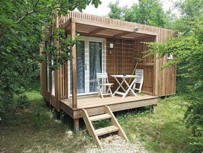 A wooden cabin with a deck, a table with chairs, and a ladder leading to the entrance. - Studnature Dunes (Dunes)