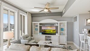 A living room with a television, sofa, coffee table, and a ceiling fan. - One Bedroom Condo at Grand Sandestin (Miramar Beach)