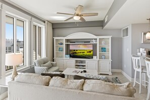 A living room with a television, sofa, coffee table, and a ceiling fan. - One Bedroom Condo at Grand Sandestin (Miramar Beach)