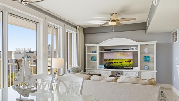 A living room with a glass table, white sofa, TV, and ceiling fan. - One Bedroom Condo at Grand Sandestin (Miramar Beach)