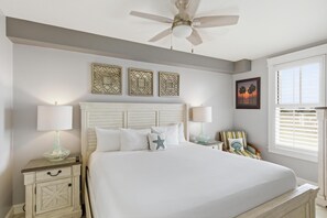 A bedroom with a bed, nightstands, a ceiling fan, wall art, and a window with blinds. - One Bedroom Condo at Grand Sandestin (Miramar Beach)