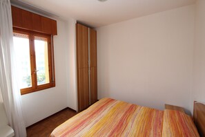 Ein Schlafzimmer mit Bett, Kleiderschrank und Fenster.