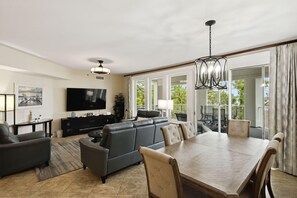A spacious living room with a large TV, a fireplace, a dining area with a wooden table and chairs, and a balcony with outdoor furniture. - 3 Bedroom and 3 Bathroom Condo in Lasata (Miramar Beach)