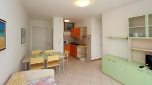 En kompakt bolig med spiseplads, tekøkken og et fjernsyn på et skab.