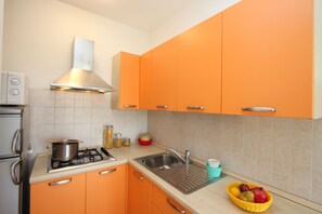 Eine Küche mit orangefarbenen Schränken, einer Edelstahl-Spüle und einem Gasherd.