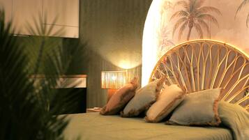 Een slaapkamer met een bed, nachtkastje, lamp en een muur met een palmboom muurschildering.