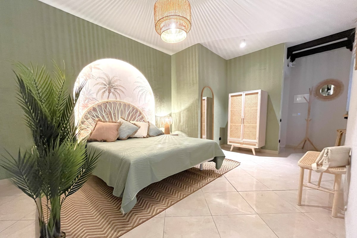 Une chambre à coucher avec un lit, une plante en pot, un miroir, une armoire et une chaise.