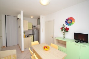 Una cocina moderna con microondas, refrigerador y comedor con mesa y sillas.