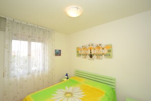 Un dormitorio con cama, mesita de noche, lámpara y una obra de arte en la pared.