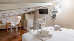A hotel room with a bed, a desk, a chair, a TV, and a mirror.