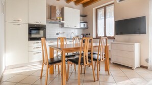 A modern kitchen with white cabinets, a wooden dining table, and chairs.