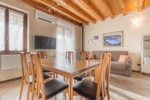 Un coin repas avec une table et des chaises en bois, un téléviseur et un tableau accroché au mur.