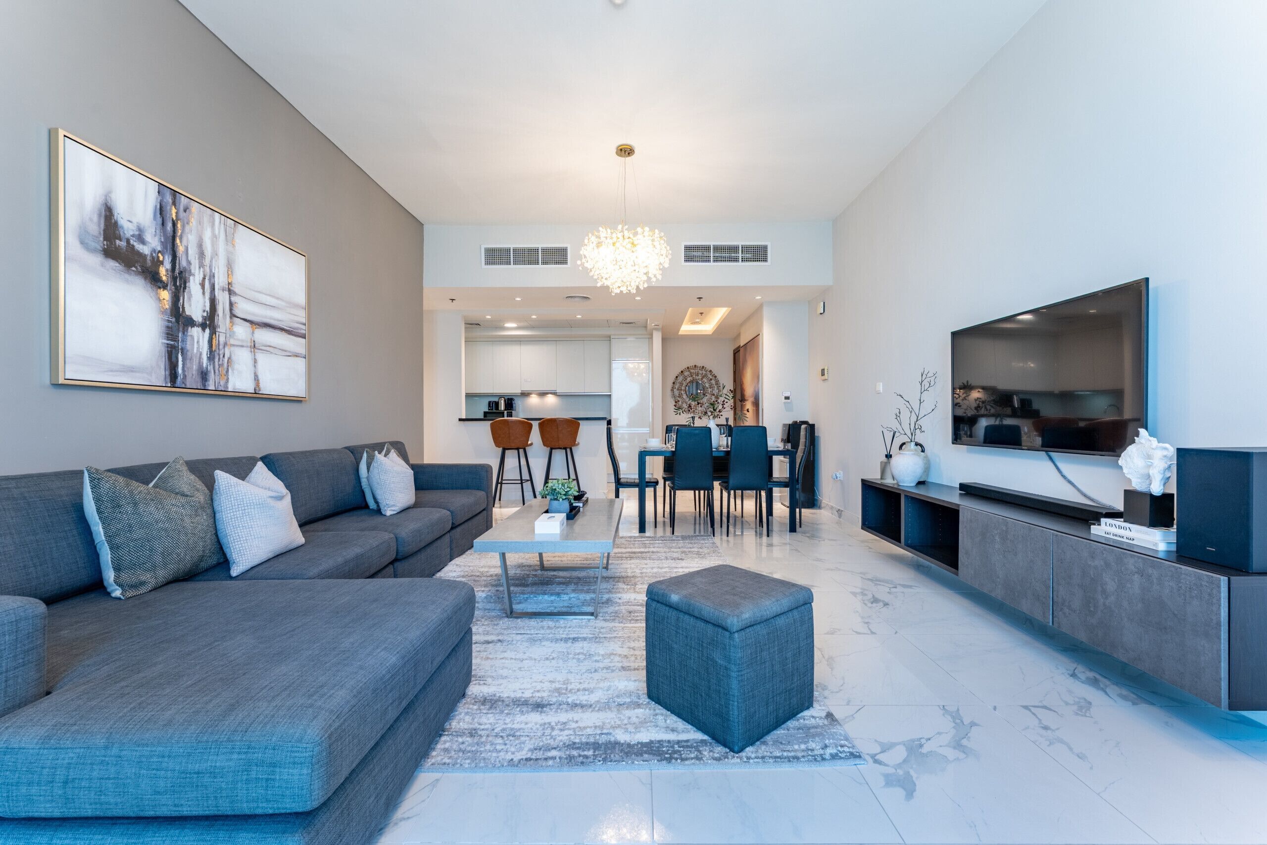 A modern living room with a grey sofa, a coffee table, and a TV on a stand.