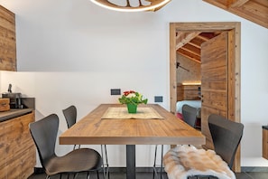 Un comedor con una mesa de madera, sillas negras, un centro de mesa con planta verde y un manto de piel en el suelo.