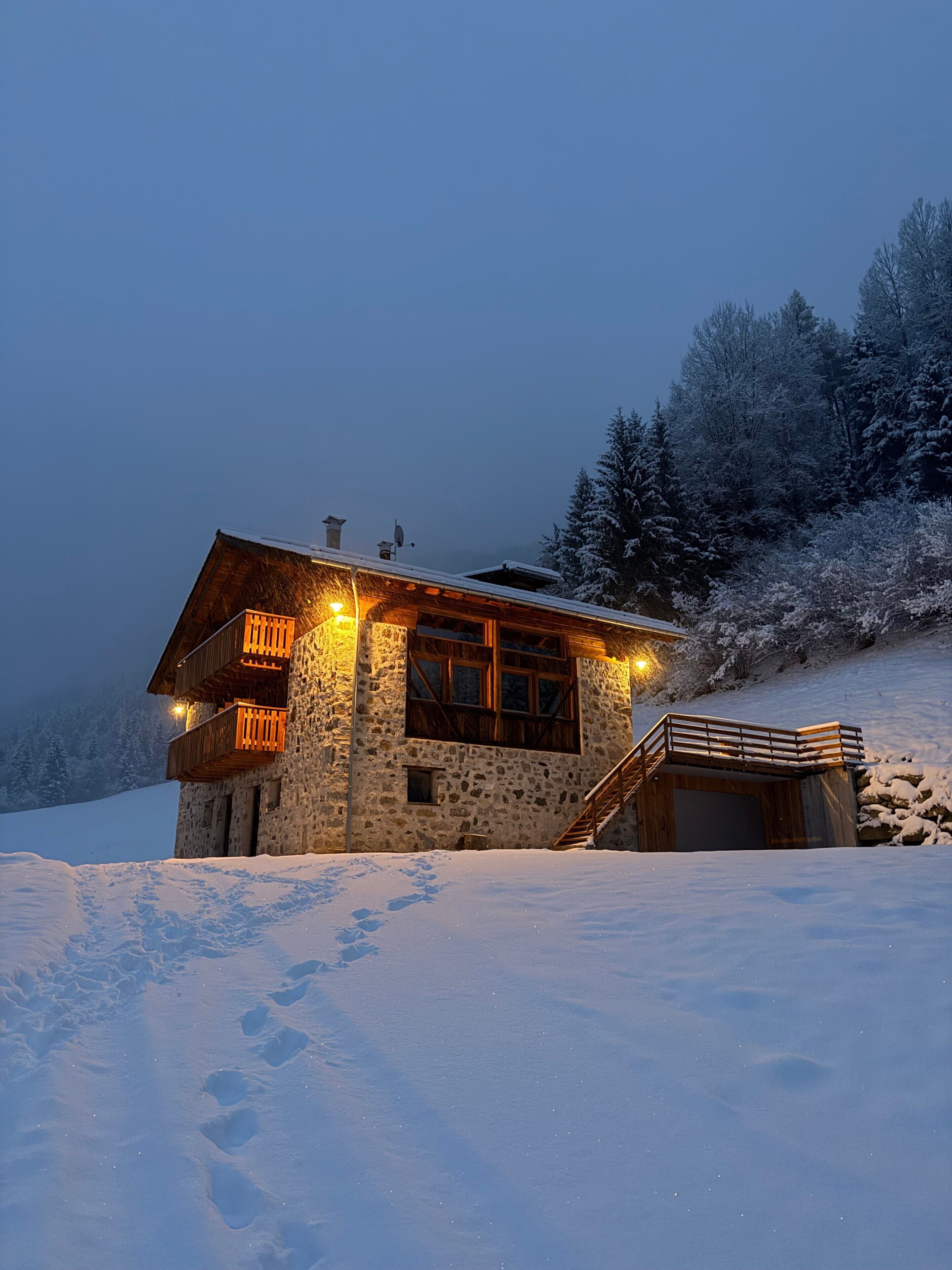 Eine Steinhütte mit einem Holzbalkon und einer Treppe zu einer Holzdiele.