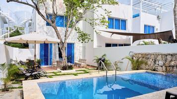 Een buitenzwembad, parasols voor strand/zwembad