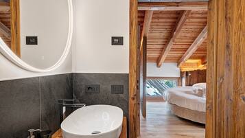 Een moderne badkamer met een groot wit wastafelblad, donkere tegels en houten balken.