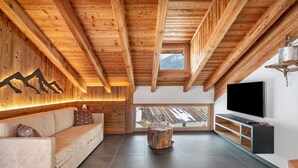 Un interno moderno con soffitto in legno, una grande televisione, un divano e vista dalla finestra.