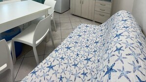 Ein kleines, sauberes Zimmer mit einem Bett, einem Schreibtisch, einem Kühlschrank, einem Fernseher und einem Schrank.