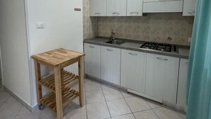 Eine kleine Küche mit weißen Schränken, einem Holztisch und einem Gasherd.