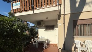 A building with a balcony, a sign reading "AFFITTA", outdoor seating, and a number "9" on the wall. - Cozy flat with private parking in Rosolina Mare (Rosolina Mare)