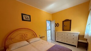 Un dormitorio con cama, cómoda, espejo y puerta que da a un balcón.