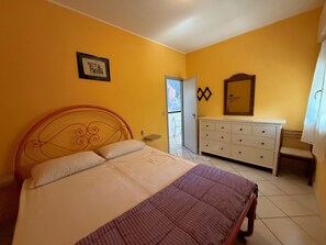 A bedroom with a bed, a dresser, a mirror, and a door leading to a balcony. - Nice family villa in Rosolina Mare (Rosolina Mare)