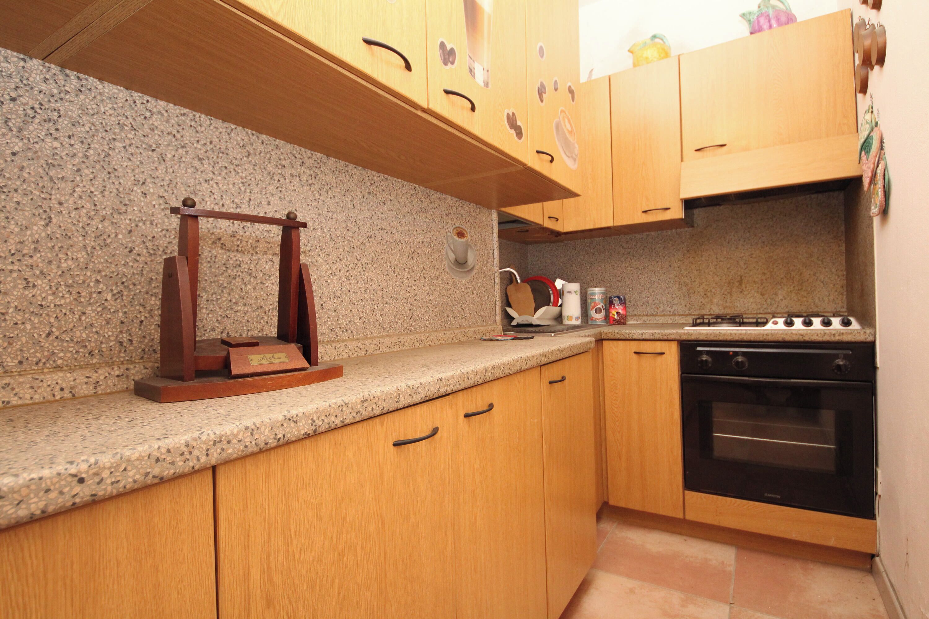 Una cocina con armarios de madera, encimera de granito, cafetera y estufa.