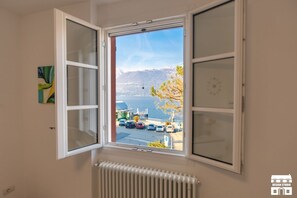 Ein Zimmer mit großem Fenster und Blick auf ein Gewässer und Berge.