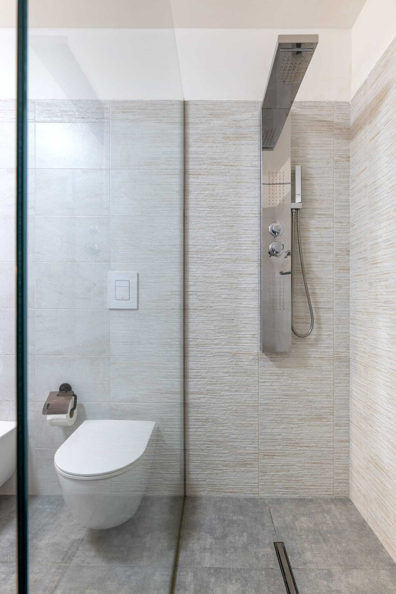 Un baño moderno con ducha, inodoro y mampara de vidrio.