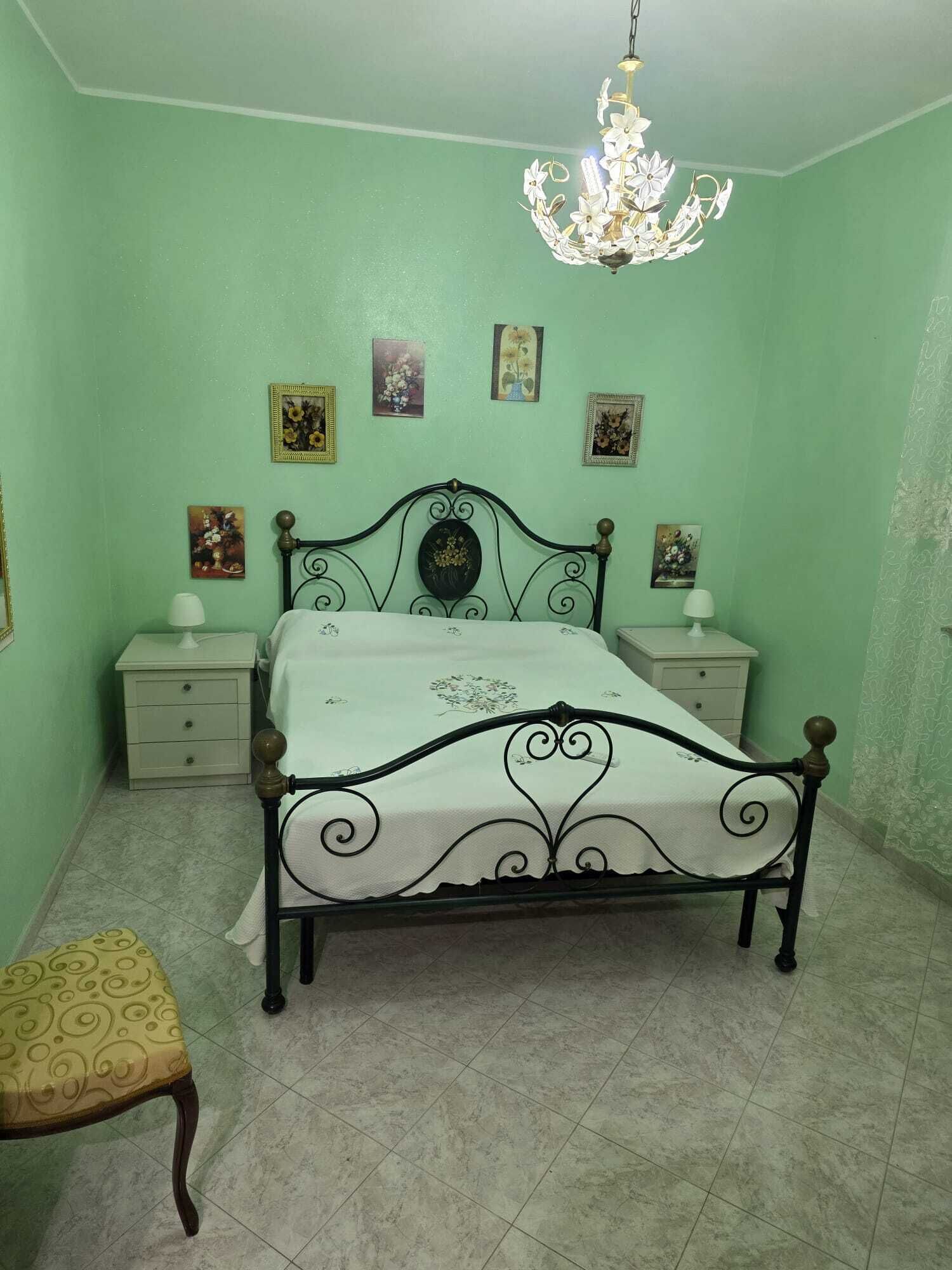 Ein Schlafzimmer mit einem Bett, Nachttischen, einem Sessel und einer Deckenleuchte.