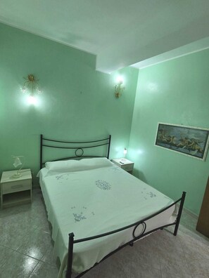 A bedroom with a bed, nightstands, a wall-mounted light fixture, and a painting. - Villa Jole Fontane Bianche (Fontane Bianche)