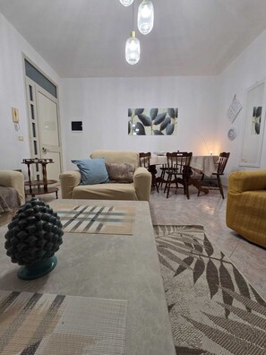 A living room with a sofa, coffee table, and a dining area with chairs and a table. - Villa Jole Fontane Bianche (Fontane Bianche)