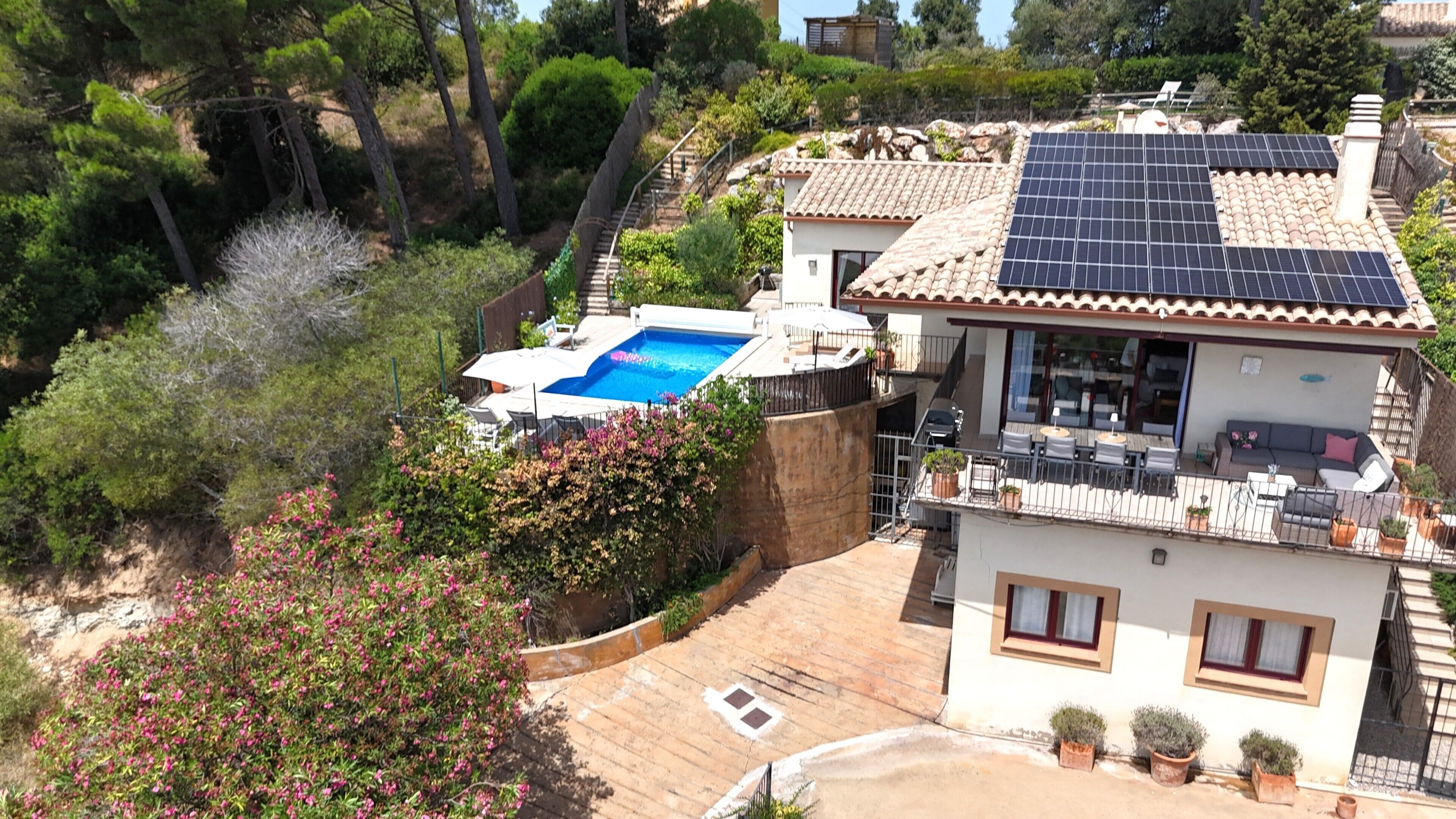 Ein Wohnhaus mit Schwimmbad, Solaranlage und Balkon mit Gartenmöbeln.