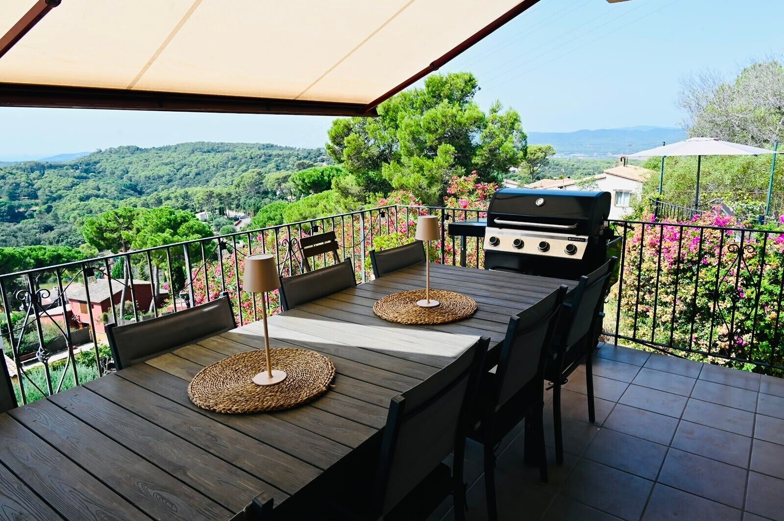 Un área de comedor al aire libre con una mesa de madera, sillas y una parrilla.