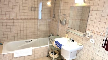 A bathroom with a bathtub, a sink, a mirror, and a shower.