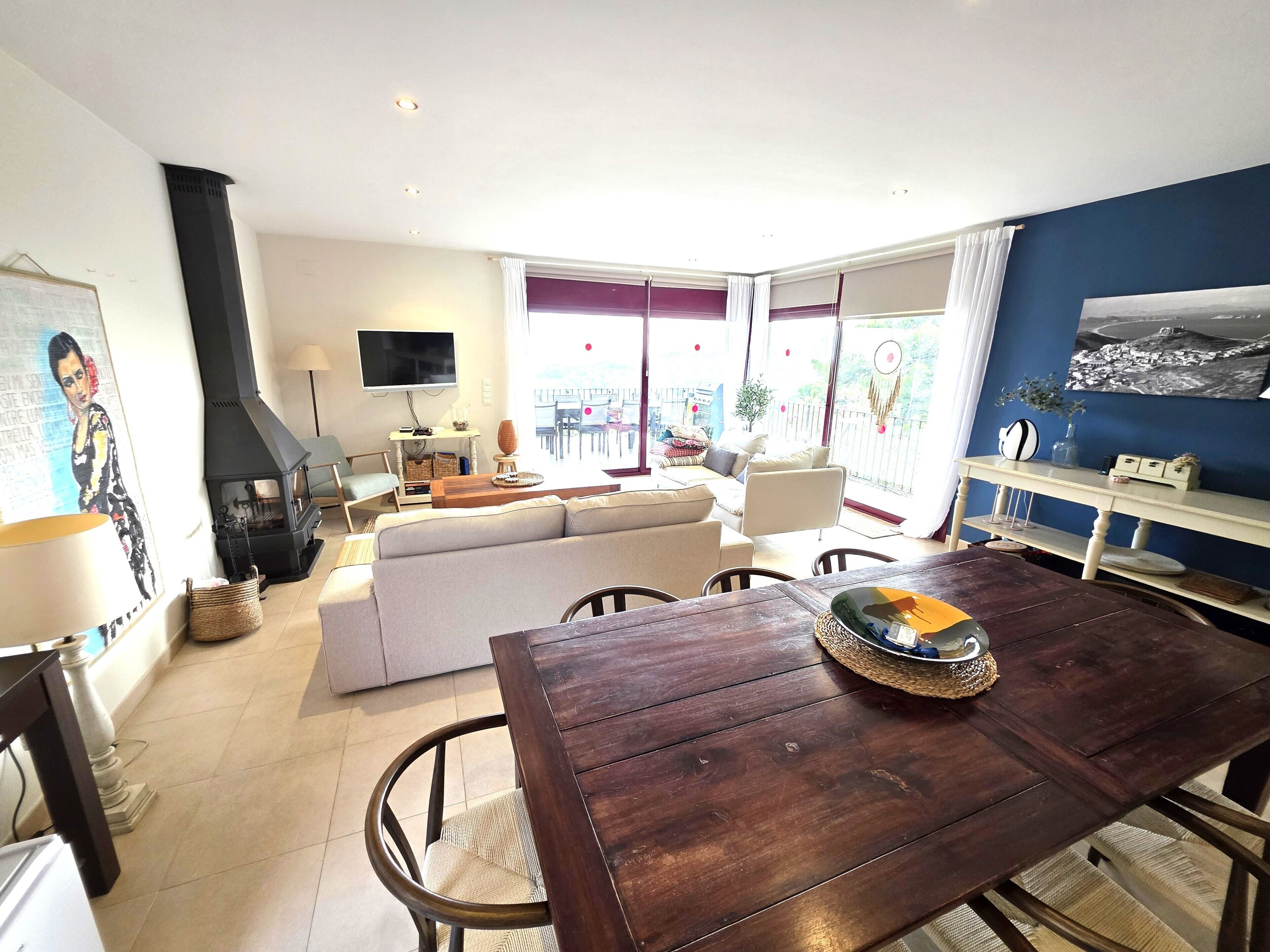 A living room with a sofa, a TV, a fireplace, and a dining area with a table and chairs.