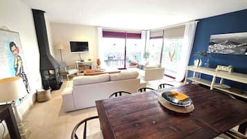 A living room with a sofa, a TV, a fireplace, and a dining area with a table and chairs.