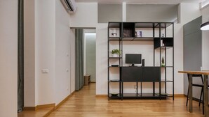 Moderni huone, jossa on puulattia, musta hyllykkö ja siinä tasainen näyttö, sekä pieni pöytä.